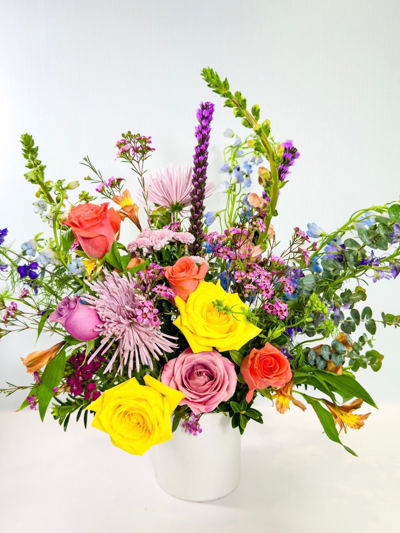 Colorful flower arrangement in a white vase on a light background