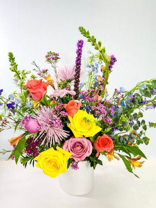 Colorful flower arrangement in a white vase on a light background